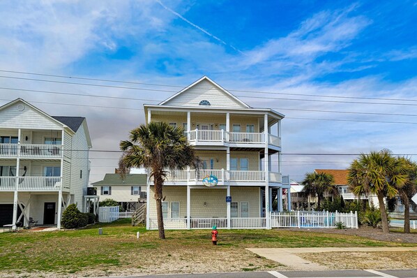 A multi-story hotel with a balcony on each floor, a swimming pool, and a palm tree in the foreground. - Dive into "Summer Days & Cooler Nights"! w/ pool! (Surf City)