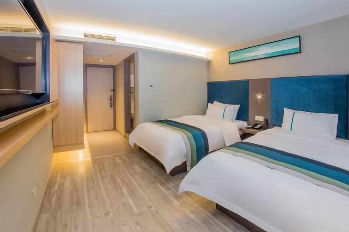 A hotel room with two beds, a TV, and a door leading to a bathroom.