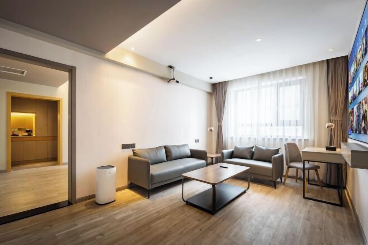 A modern living room with a sofa, coffee table, and a desk area.