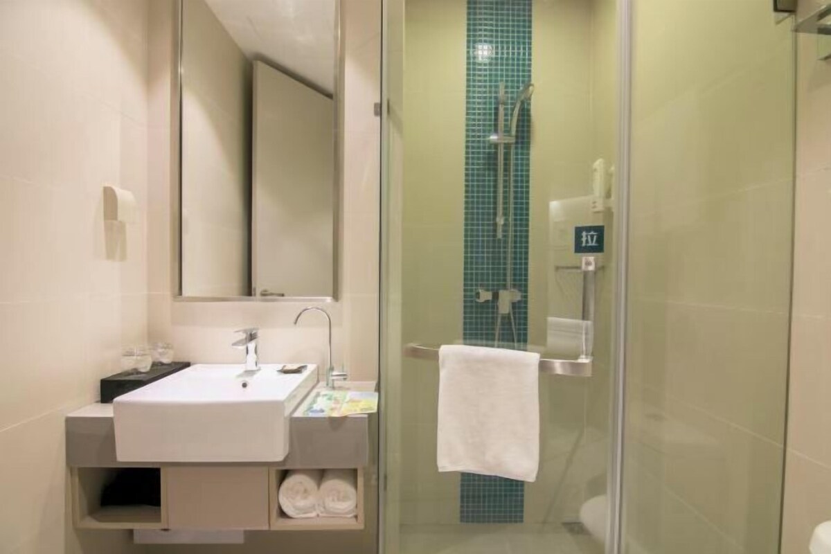 A modern bathroom with a glass-enclosed shower, a white sink, and a mirror.