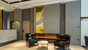 Un hall d’entrée moderne avec un comptoir d’accueil, deux fauteuils en cuir, une table basse ronde et une cheminée.