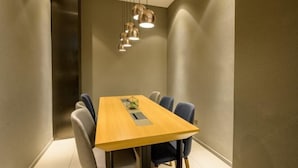 Un espace repas moderne avec une table en bois et six chaises, un luminaire suspendu et un plafond avec des encastrements.