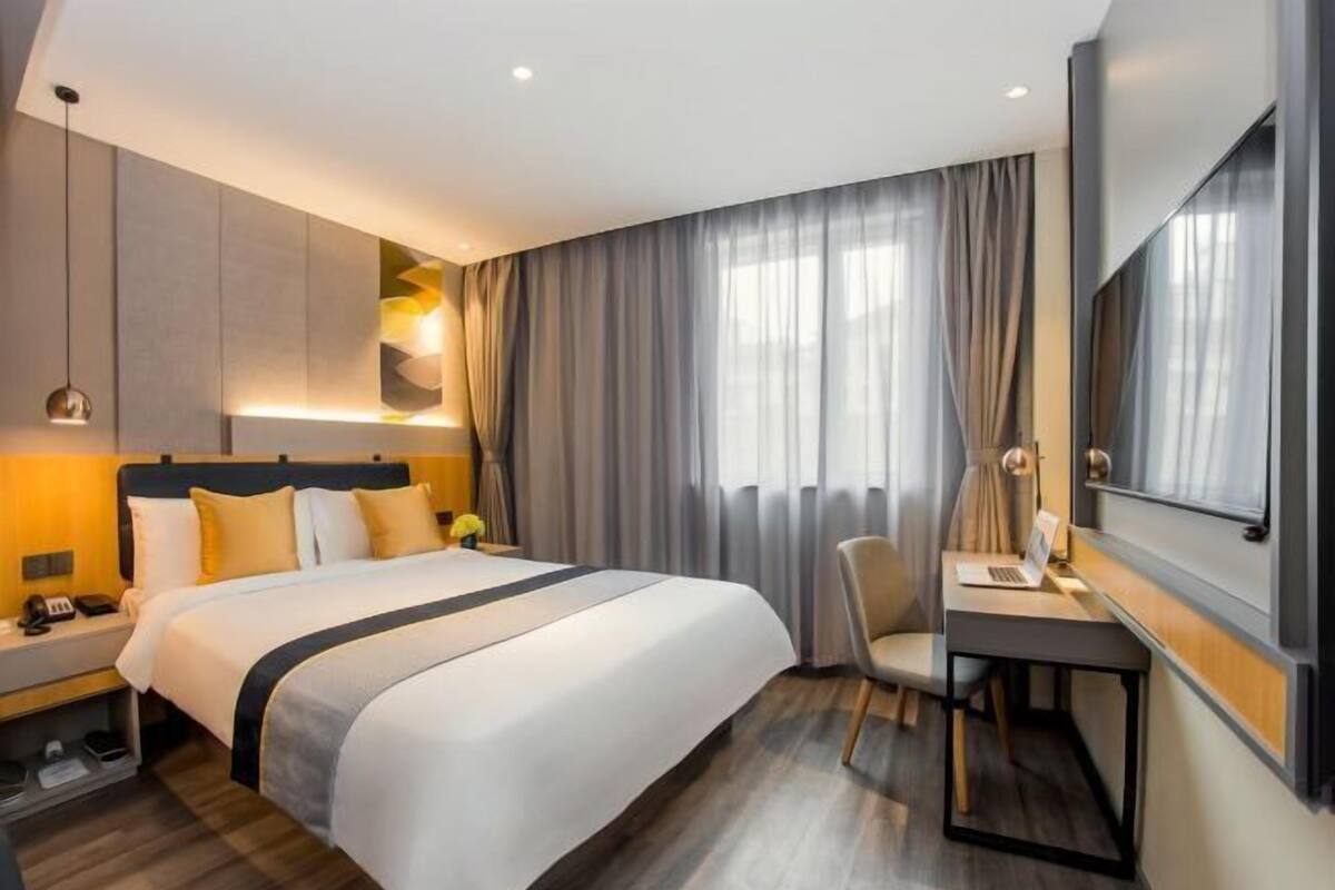 A modern hotel room with a large bed, a desk, and a chair.