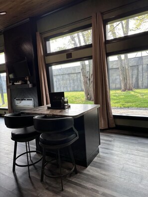 A modern kitchen with a bar area, large windows, and a view of the backyard.