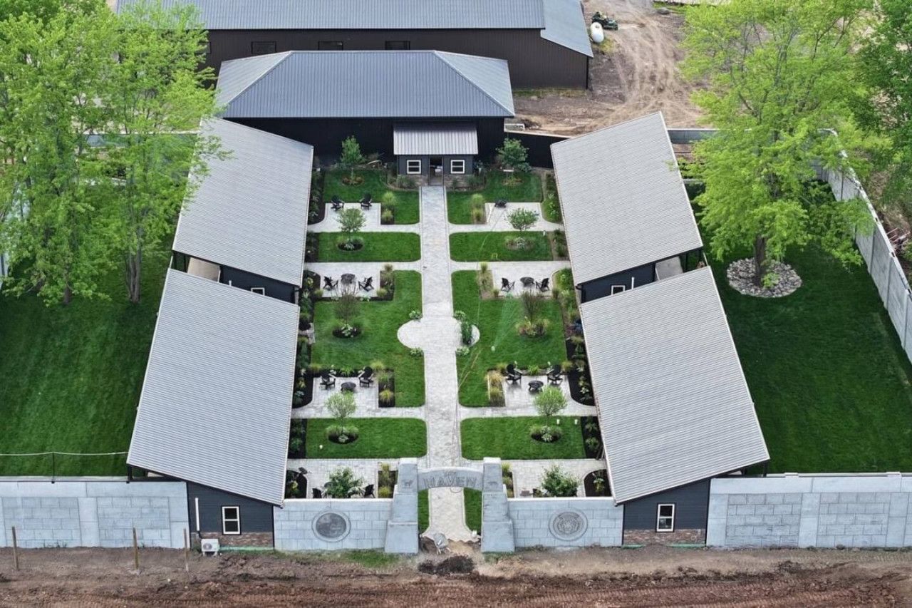 A symmetrical building with a central courtyard, surrounded by trees and a well-maintained lawn.