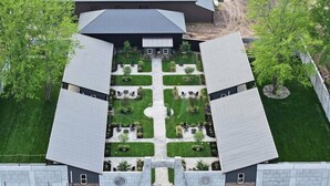Een symmetrisch gebouw met een centrale binnentuin, omringd door bomen en een verzorgd gazon.