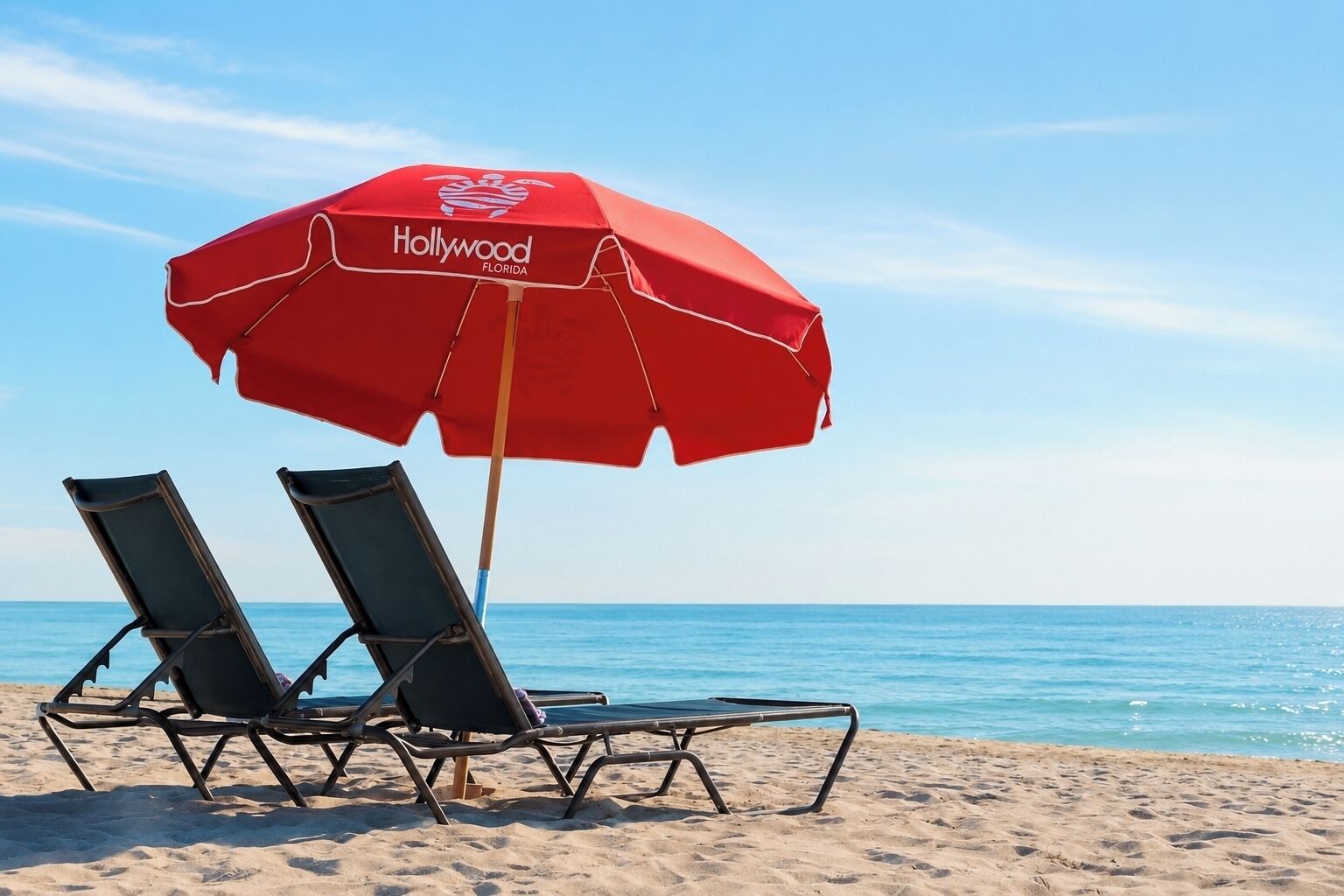 En strandscen med två solstolar och ett rött parasoll med Hollywood Florida-motiv.
