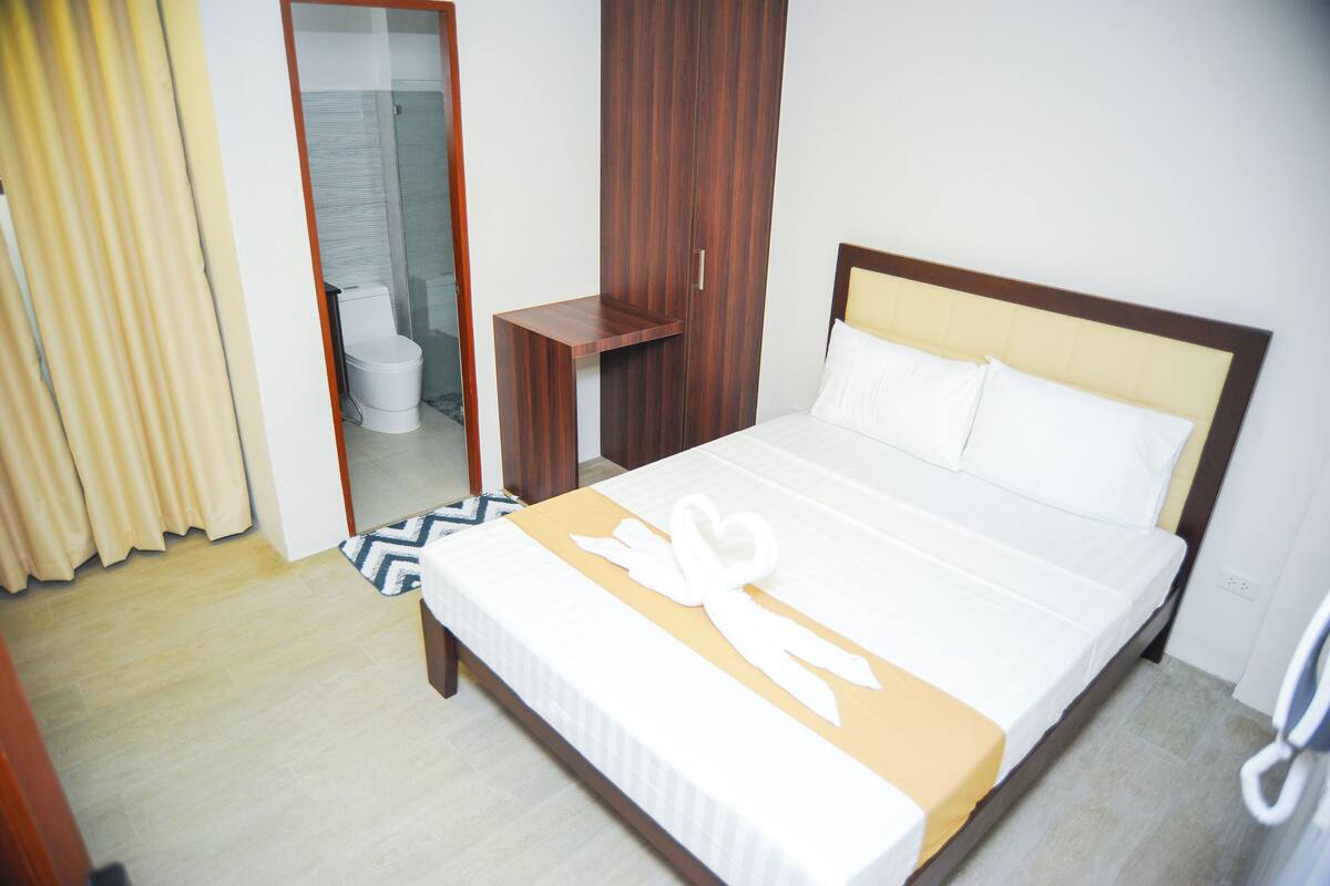 Ein Hotelzimmer mit einem Bett, einem Holzschrank, einem kleinen Tisch und einem Spiegel.