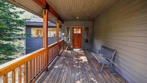 A covered porch with a wooden railing, a bench, and a door leading to a building. - Stunning Peak Views-Spacious Bear Creek 4Bdrm Home (Alpine Meadows)