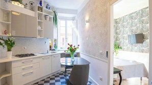 Una cocina moderna con gabinetes blancos, piso a cuadros y un comedor con mesa y sillas.