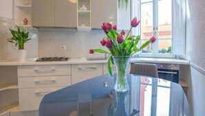 Una cocina moderna con armarios blancos, un florero de cristal con flores y vistas al exterior por una ventana.