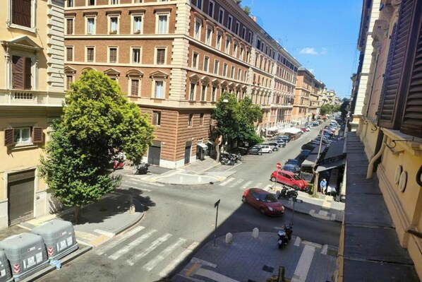 Vista de una calle con edificios de varios pisos, automóviles estacionados y un paso de peatones.