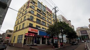 A multi-story building with a yellow facade and several ground-floor shops.