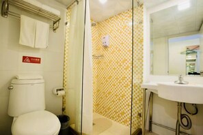 A bathroom with a toilet, shower, and sink.