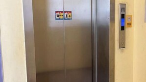 An elevator with a control panel and two safety signs on the door.