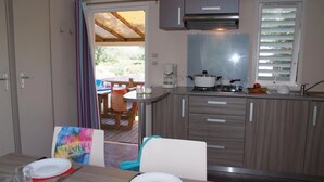 Cocina compacta con estufa a gas, cafetera y ventana con persianas.
