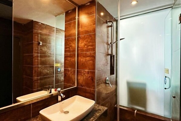 Un baño moderno con un espejo grande, un lavabo y una cabina de ducha con paredes de vidrio.