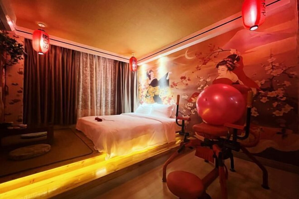 Quarto com cama, cortinas, um mural na parede e uma bola de ginástica vermelha.