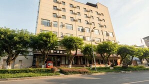 A multi-story hotel with a flat facade, air conditioning units, and a well-maintained front garden with trees and shrubs. - Chongqing Jiayumei Hotel (Chongqing)