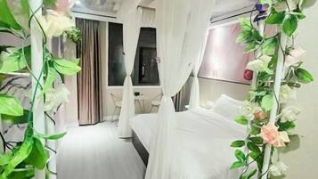 A bedroom with a bed, curtains, and a plant.