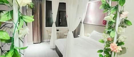 A bedroom with a bed, curtains, and a plant.