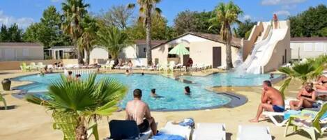 A swimming pool area with lounge chairs and a water slide.