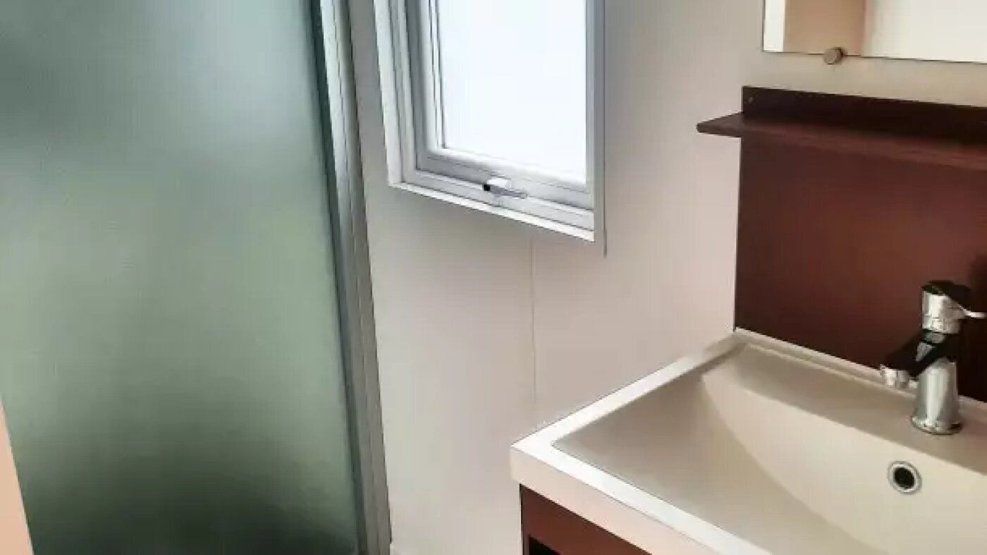 Un baño con ventana, lavamanos y espejo.