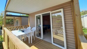 A covered deck with a table and chairs, a sliding glass door, and a view of the backyard.