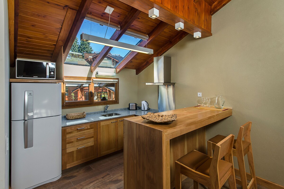 A modern kitchen with wooden cabinets, a built-in microwave, and a large island with seating.