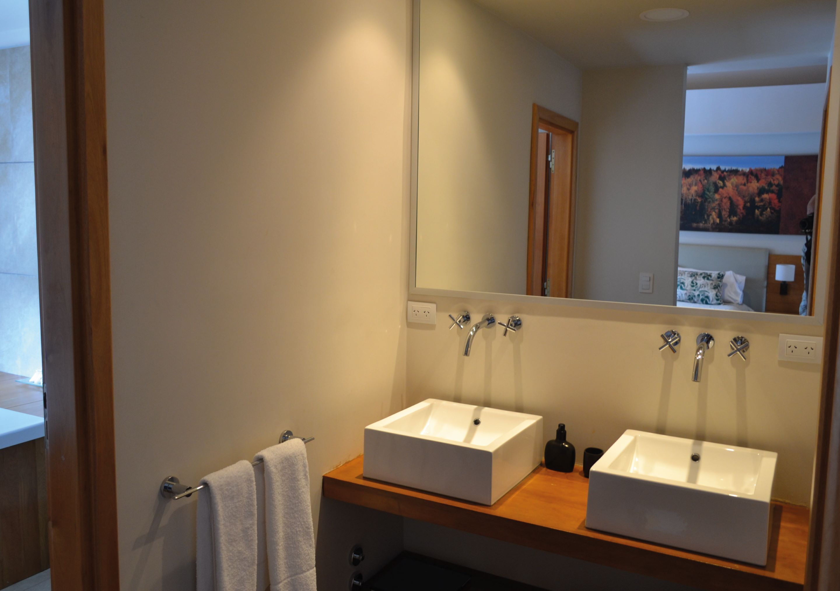 Un baño con dos lavamanos, un espejo y un perchero para toallas.
