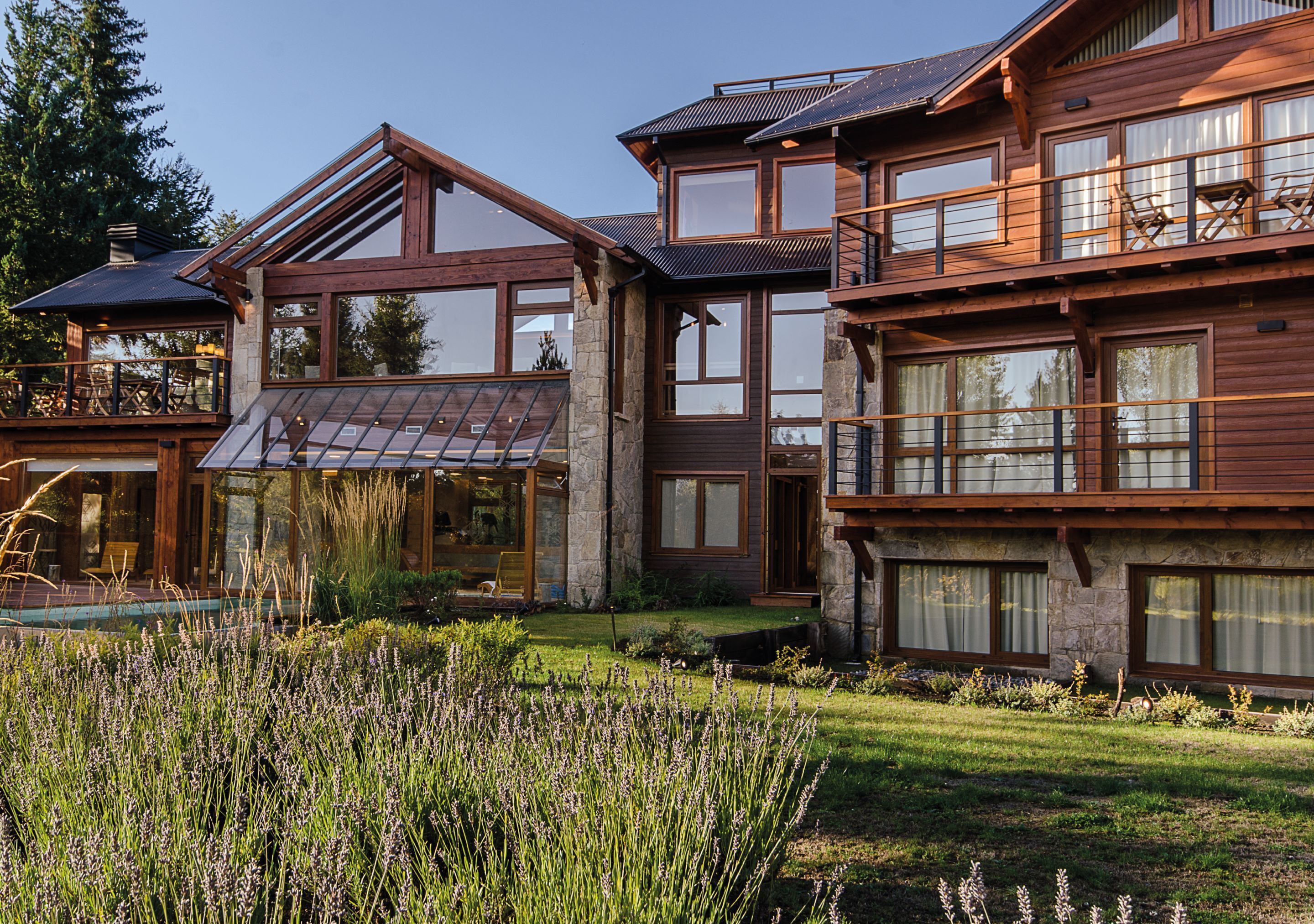 A multi-story wooden house with large windows and a stone foundation.
