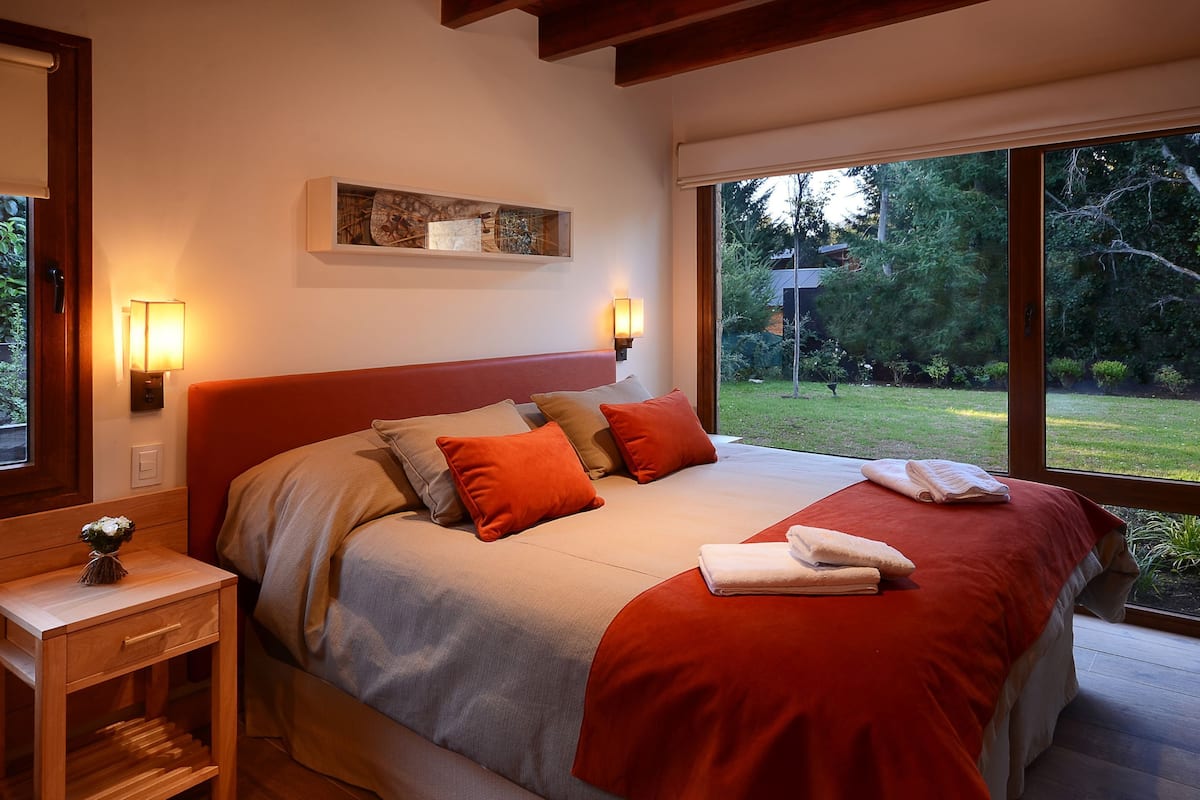 Une chambre à coucher avec un grand lit, deux lampes de chevet, une table de chevet et une fenêtre donnant sur l’extérieur.