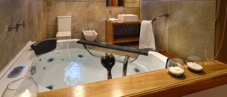 A modern bathroom with a large bathtub, a vanity with a sink, a toilet, and a shower area.