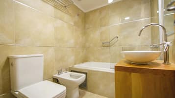 A modern bathroom with a toilet, bidet, and bathtub.