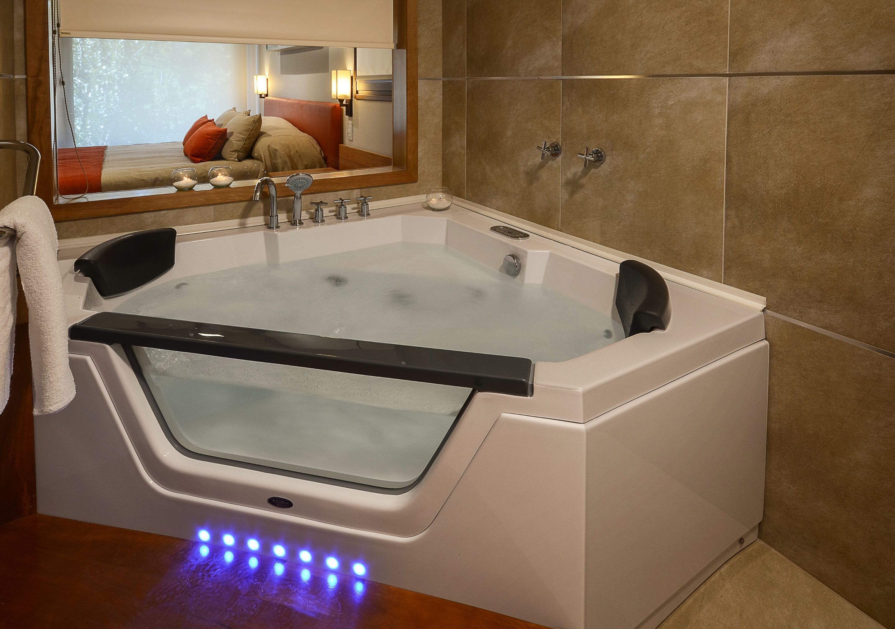 A modern bathroom with a large bathtub, a mirror, and a window.