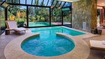 Una piscina techada, una piscina al aire libre, sombrillas