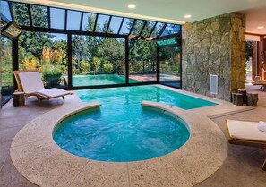 Una piscina techada, una piscina al aire libre, sombrillas