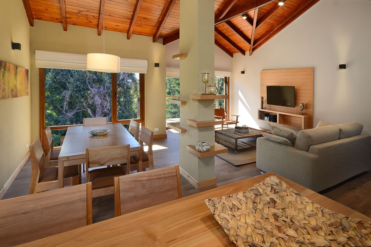 A spacious living area with a wooden dining table, sofa, and TV.
