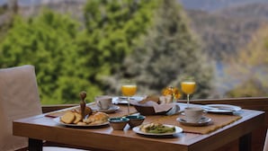 Een ontbijttafel met borden eten, glazen sinaasappelsap en uitzicht op bergen.