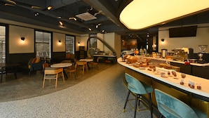 A modern bar area with seating, a counter with various items, and a staircase leading to another level. - Luxeur Jakarta - Setiabudi (Jakarta)