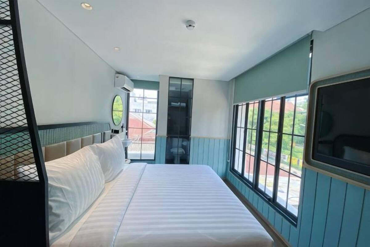 A hotel room with a bed, a window, and a door.
