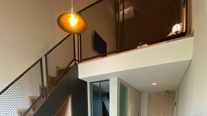 A modern interior with a staircase, a seating area, and a large window. - Luxeur Jakarta - Setiabudi (Jakarta)