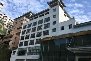 Un edificio de varios pisos con un diseño arquitectónico moderno, con una serie de balcones y grandes ventanales.
