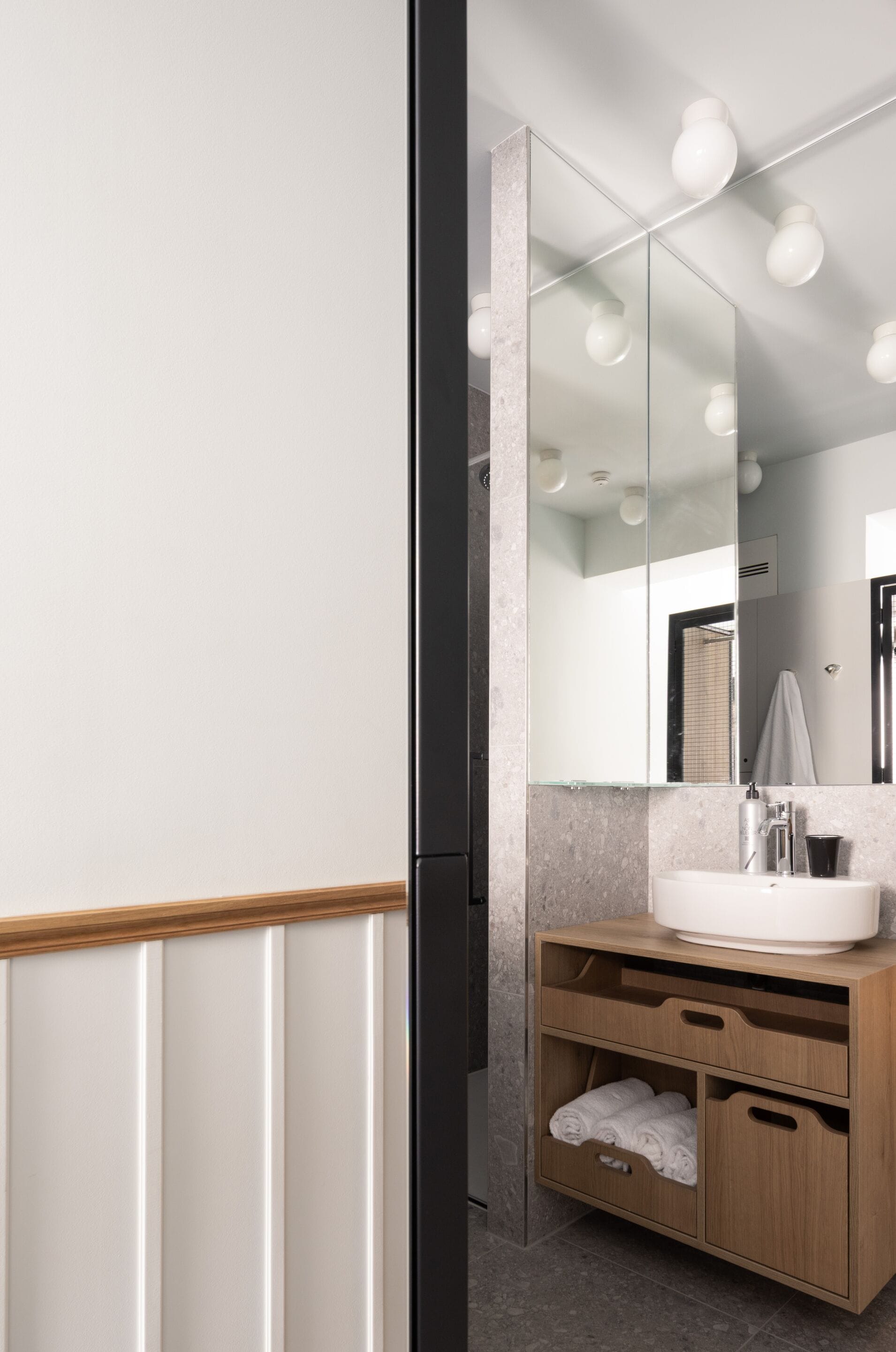 Un baño moderno con un espejo grande, un lavamanos y un mueble de tocador de madera con cajones.