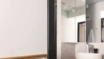 Un baño moderno con un espejo grande, un lavamanos y un mueble de tocador de madera con cajones.