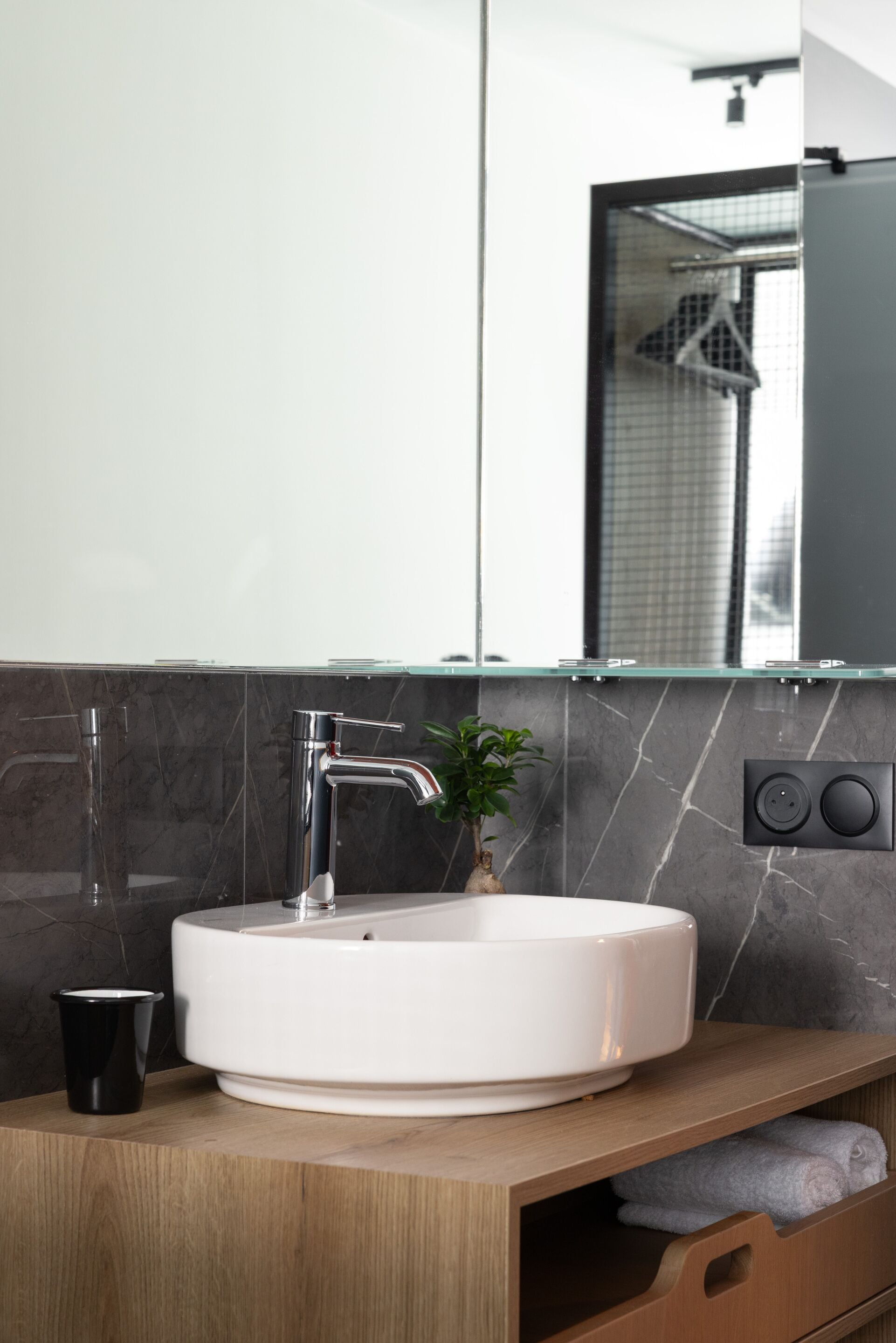 Ein modernes Badezimmer mit einem weißen Waschbecken, einem Spiegel und einer Marmor-Spritzschutzwand.