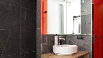 Une salle de bain moderne avec un meuble-lavabo en bois, un lavabo blanc et un grand miroir.