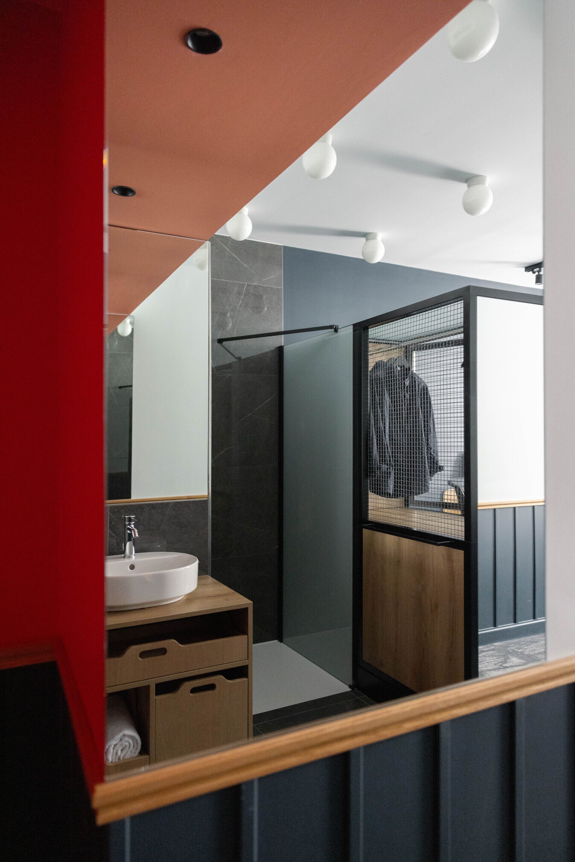 A modern bathroom with a wooden vanity, a white sink, and a glass shower enclosure.