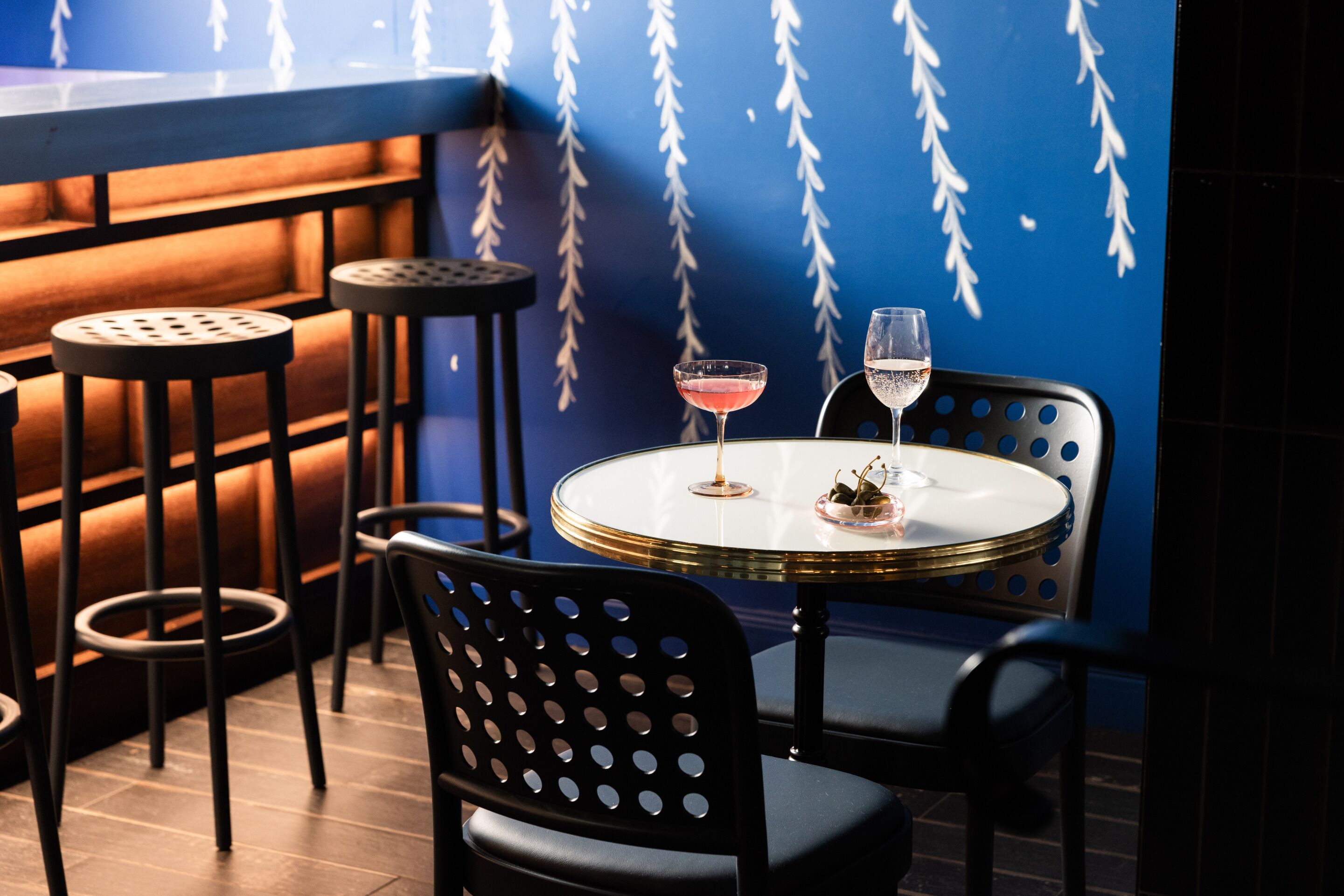 Una zona de bar con una mesa redonda, dos sillas y un taburete.