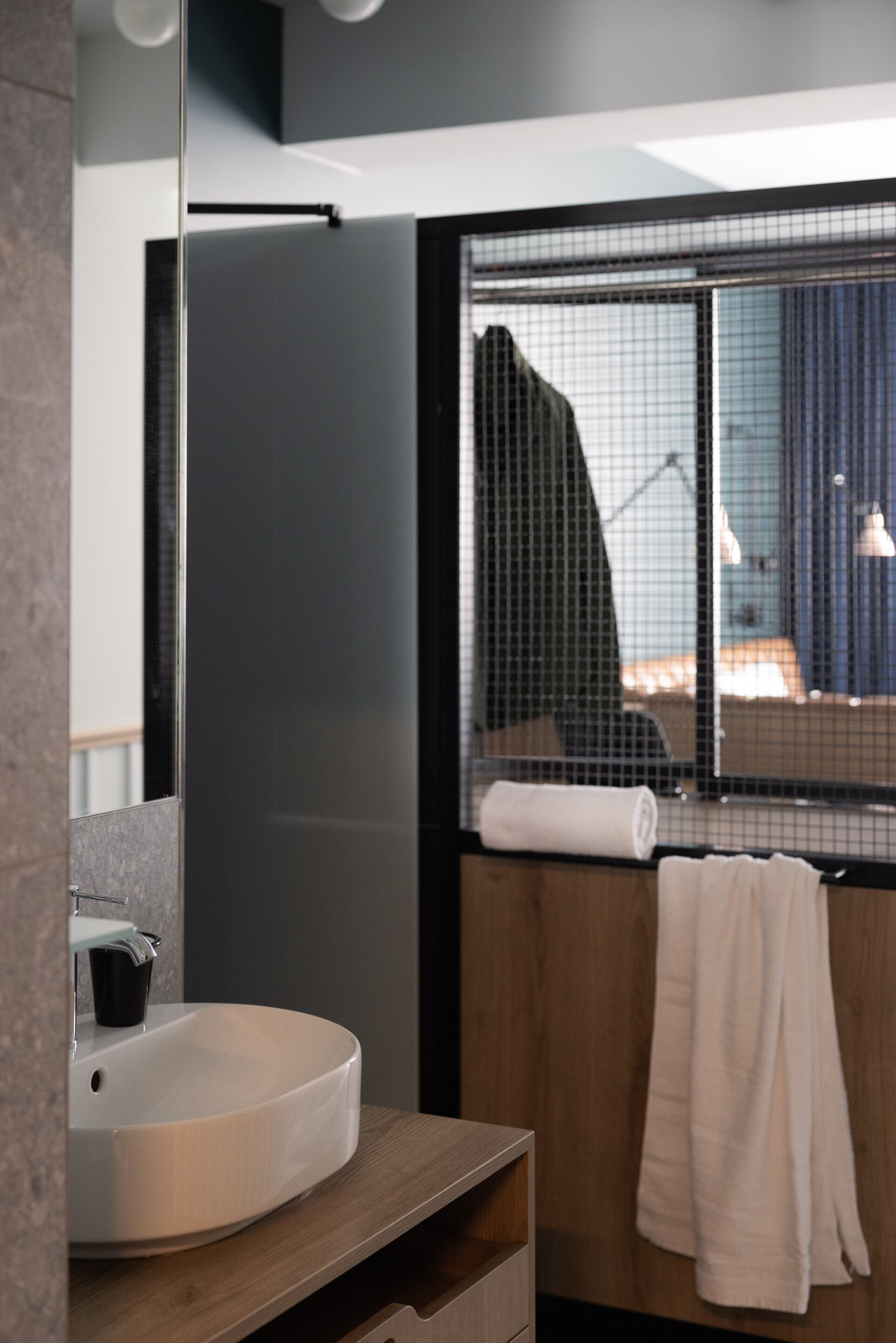 A modern bathroom with a round sink, wooden vanity, and a large mirror.
